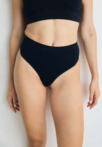 Black high-waisted briefs made of soft, stretchy fabric. Smooth texture with a wide waistband and seamless edges.
