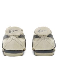 Sneaker in suede bianco con dettagli grigi, caratterizzate da una finitura testurizzata, tacco arrotondato e logo "Tiger" ricamato sul retro.