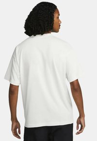 Vit kortärmad T-shirt med avslappnad passform, mjuk textur och rundad halsringning, sedd bakifrån.