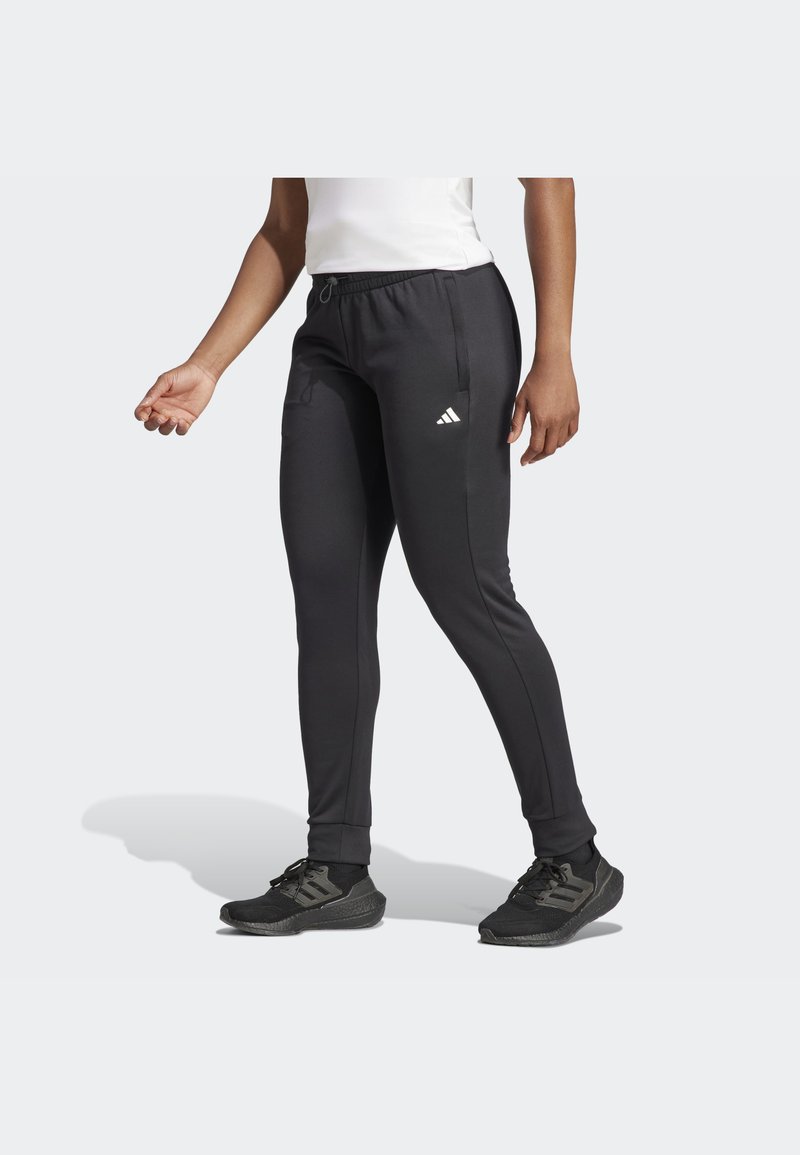 Pantalones deportivos negros con un ajuste slim, cinturilla elástica con cordón, y acentos de logo blanco en el costado. Textura de tela suave.