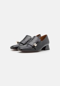 Zwarte leren schoenen met een spitse neus, lage blokhak en twee decoratieve banden met een gouden accent aan de voorkant.