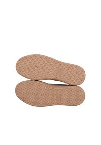 Soli delle scarpe in gomma marrone con un motivo a nido d'ape, caratterizzati da una leggera curvatura e un marchio in rilievo. Texture liscia con bordi arrotondati.