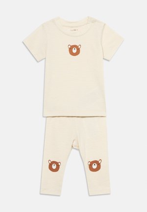 Baby pyjamasæt med creme- og hvide striber, kortærmet top og bukser med brune bjørneansigter på bryst og knæ.