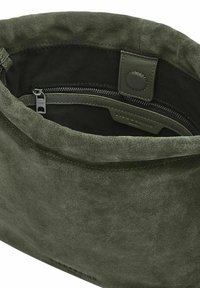 Borsa in suede verde oliva con una trama morbida; presenta un compartimento con zip e una chiusura a scatto. L'interno è foderato in tessuto nero.