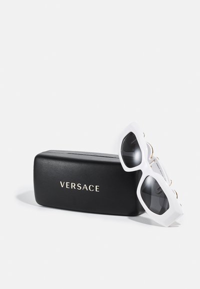 Ochelari de soare albi cu un design unghiular și lente întunecate vin într-o carcasă rectangulară neagră cu branding auriu „VERSACE”. 