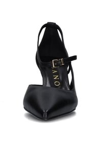 Scarpa nera in pelle con tacco alto, punta affilata, cinturino alla caviglia e dettaglio della fibbia dorata; texture liscia con un design aderente.