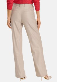 Beige wijde broek in een soepele stof, met twee achterzakken en een aansluitende taille met riemlussen.