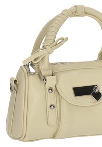 Bolso de color crema hecho de material sintético, con un diseño estructurado, asa corta, herrajes plateados y un detalle de charm en forma de corazón.
