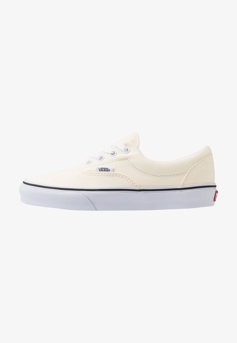Baskets basses blanches Vans avec lacets blancs, bande noire sur la semelle en caoutchouc blanche et étiquette logo Vans sur le côté.