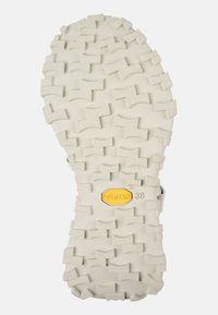 Suela de Vibram blanca con un patrón de relieve texturizado, que cuenta con ondulaciones y crestas profundas para mayor tracción; incluye un logotipo amarillo y talla 38.