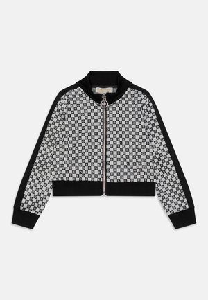 Chaqueta recortada en blanco y negro con patrón de tablero de ajedrez con texto "KORS", cierre de cremallera, cuello y puños acanalados.