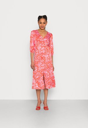 Vestido com padrão vermelho e rosa, com decote em V, mangas bufantes de três quartos e comprimento até a metade da panturrilha. Possui uma fenda na parte da frente e botões na frente.
