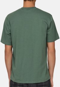 Kortärmad t-shirt med rund halsringning i mörkgrön bomull, med en slät yta och en rak fåll vid midjan. Minimalistisk design.