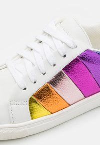 Biała sneakerka z metalicznymi paskami w kolorze purpurowym, różowym, pomarańczowym i złotym. Posiada białe sznurowadła i teksturowane wykończenie ze skóry.
