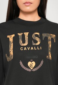 Black cotton T-shirt featuring large, distressed gold lettering and graphic design with laurel wreath and heart details.