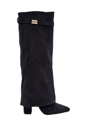 Botte en suede noir avec une tige montée jusqu'au genou, un bout pointu, un talon carré et un accent en métal doré sur la sangle supérieure.
