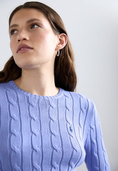 Light purple cable-knit sweater with a round neckline and long sleeves; features textured pattern and small logo accent on the chest.