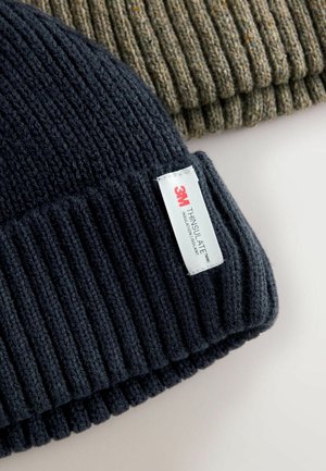 Caciula din tricot negru cu model ondulat, având etiqueta albă cu textul "3M THINSULATE". Textura este moale, potrivită pentru a oferi căldură în vreme rece.