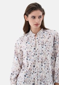 Lightweight floral blouse featuring purple, blue, and brown patterns. It has a pleated design, long sleeves, a stand collar, and button front closure.