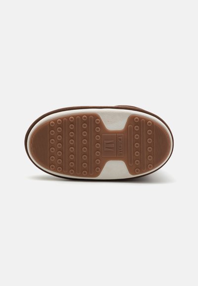 Brown rubber sole with a textured surface featuring circular and ridged patterns, accented with a cream-colored midsole.