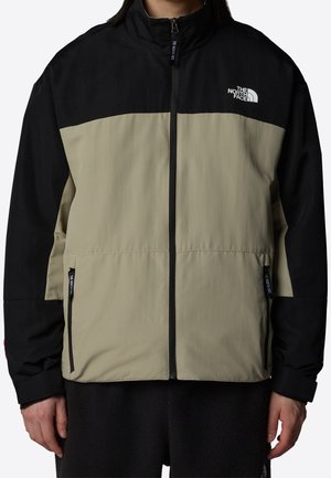 Zweifarbige North Face Jacke in Schwarz und Beige mit Frontreißverschluss und Reißverschlusstaschen an den Seiten, getragen von einer Person.
