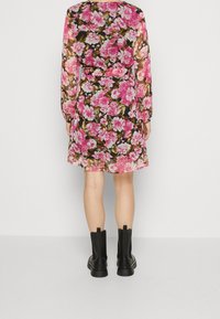 Blommig klänning i svart med rosa och vita blommor, med långa ärmar, avslappnad passform och insydd midja. Matchat med svarta ankelstövlar.