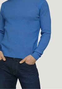 Maglione blu lavorato a maglia con motivo strutturato, scollo rotondo e polsini e orlo a coste, abbinato a jeans in denim scuro.