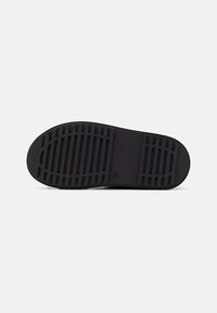 Semelle de chaussure en caoutchouc noir au design plat, présentant un motif de bande de parallèles et de rainures pour l'adhérence. Texture lisse, sans accents.