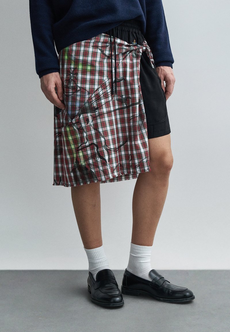 Ruudulise mustriga (punane ja roheline) kilti meenutav riideese, millel on must ala, elastne vöökoht ja küljes nöör. Mustad kingad ja valged sokid.