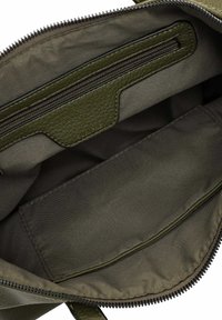 Grön tygväska inuti med en texturerad läderficka med dragkedja, slätt foder och ett rektangulärt tilläggsrum. Dragkedjestängning ingår.
