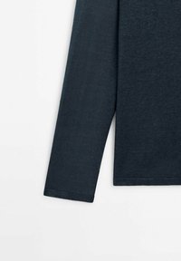 Tissu en tricot bleu marine foncé à manches longues montrant la manche et une partie du torse sur fond blanc.