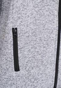 Gray knitted fabric with a speckled pattern, featuring a black zippered pocket at the side for storage and a smooth texture.