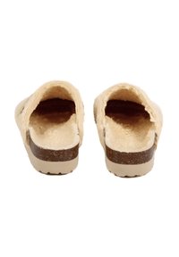 Sabots beige à enfiler avec une texture douce et moelleuse, un design profil bas, et une semelle en liège brunâtre tachetée. Style ouvert à l'arrière pour un enfilage facile.