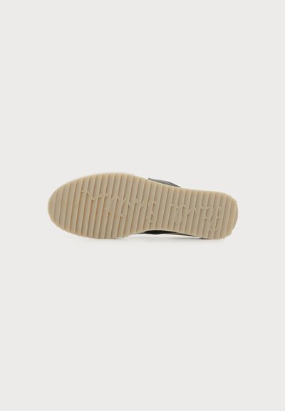 Semelle de chaussure avec des rainures horizontales et le nom de la marque « trwrds London » embossé sur la partie inférieure en caoutchouc beige clair.