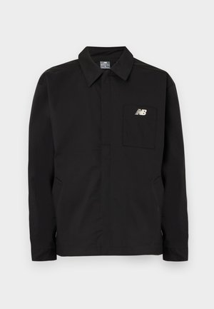 Schwarze Nylonjacke mit Kragen-Design, ausgestattet mit einer Brusttasche und dem New Balance-Logo. Glatte Textur und gerader Schnitt.