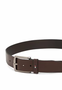 Bruine leren riem met een zilveren metalen gesp, rechthoekige vorm, met een klein logoaccent nabij de gesp. Gladde textuur, minimalistisch ontwerp.