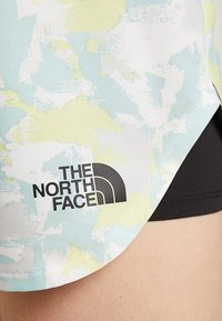 Lätt atletisk tröja med ett färgstarkt abstrakt mönster i ljusgrönt och blått, med en svart The North Face-logotyp på fållen.