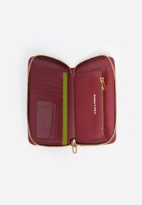 Cartera de cuero burdeos con cremallera y herrajes dorados, múltiples ranuras para tarjetas, un bolsillo transparente para la identificación y una ranura de acento verde. Textura suave y diseño compacto.