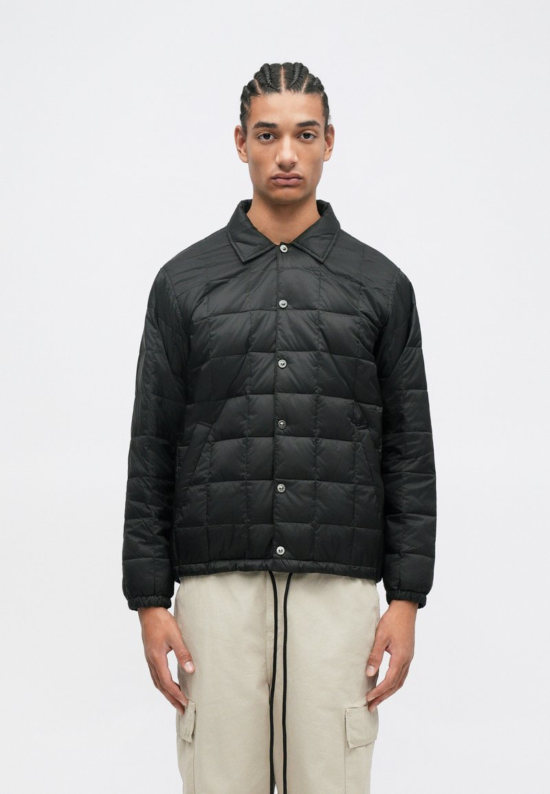Sort quiltet puffer-jakke med knaplukning, spidse krave og ribbet kant. Har en glat, blank finish og standard pasform.