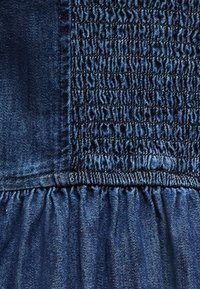 Κοντινή λήψη μπλε υφάσματος τζιν με ελαστική ρίγα και λεπτομέρειες ραφής με πτυχώσεις.