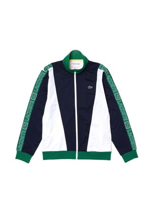 Laivastonsininen, valkoinen ja vihreä vetoketjullinen takki, jossa "Lacoste"-brändäys hihoissa ja krokotiililogo rinnassa, vihreä kaulus ja hihansuut.