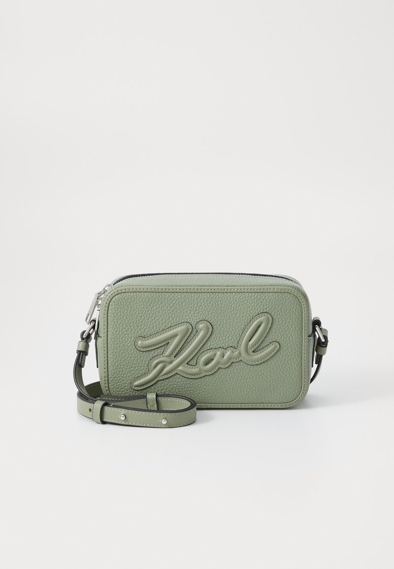 Grüne, strukturierte Leder-Umhängetasche mit erhobenem Logo, Reißverschluss und verstellbarem Riemen. Rechteckige Form mit abgerundeten Kanten.