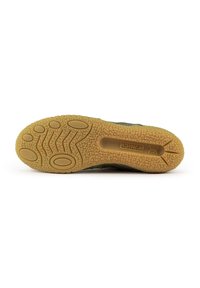 Sole della scarpa con una base in gomma beige testurizzata che presenta vari motivi e grip per la trazione; materiale superiore verde non visibile.
