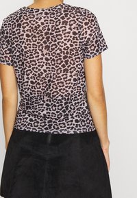 Camiseta de leopardo negra y rosa con mangas cortas, escote redondo, textura suave, combinada con una falda de ante negra.