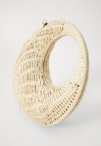 Borsa rotonda intrecciata in beige chiaro, con manico circolare e superficie testurizzata, realizzata in materiale naturale con un design senza cuciture.