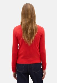 Maglione rosso a maglia con maniche lunghe, vita aderente e design semplice. Tessuto morbido, scollo rotondo, senza motivi o accenti visibili.