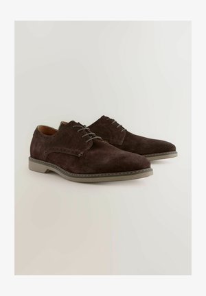 Chaussures habillées en daim marron avec un bout pointu, un design à lacets et de subtiles perforations. Semelle en caoutchouc gris avec un accent cousu.