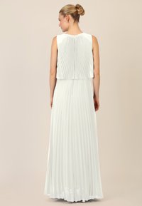 Witte plissé maxi-jurk met een mouwloze, gelaagde top en een sluiting aan de achterkant; lange, vloeiende rok zorgt voor een gladde, gestructureerde uitstraling.