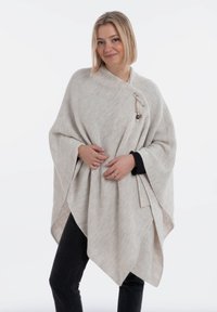 Hellgrauer gestrickter Poncho mit strukturiertem Finish, ausgestattet mit einem seitlichen Knopfverschluss und einem dreieckigen Design. Trägt man über schwarzer Kleidung.