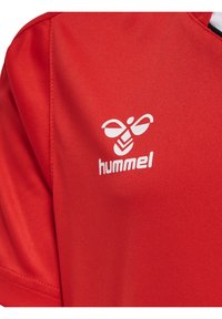 Jersey atlético rojo hecho de una tela sintética suave, con un logo blanco de Hummel en el área izquierda del pecho y acentos en negro contrastantes.